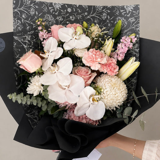 Bouquet of premium white orchids paired with blush roses and delicate seasonal blooms, this arrangement blends timeless beauty with modern luxury. Flower delivery across Castle Hill, Ryde and Parramatta.