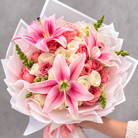An elegant bouquet of pink lilies and pink and white roses beautifully wrapped and ready to gift - flower delivery Sydney