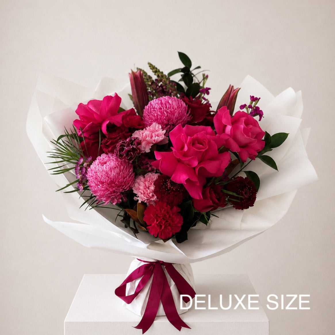 Red a Pink Bouquet featuring pink lilies, red roses and seasonal flowers wrapped in white paper Available for same-day delivery to Castle Hill, Parramatta, Ryde And across Sydney. 