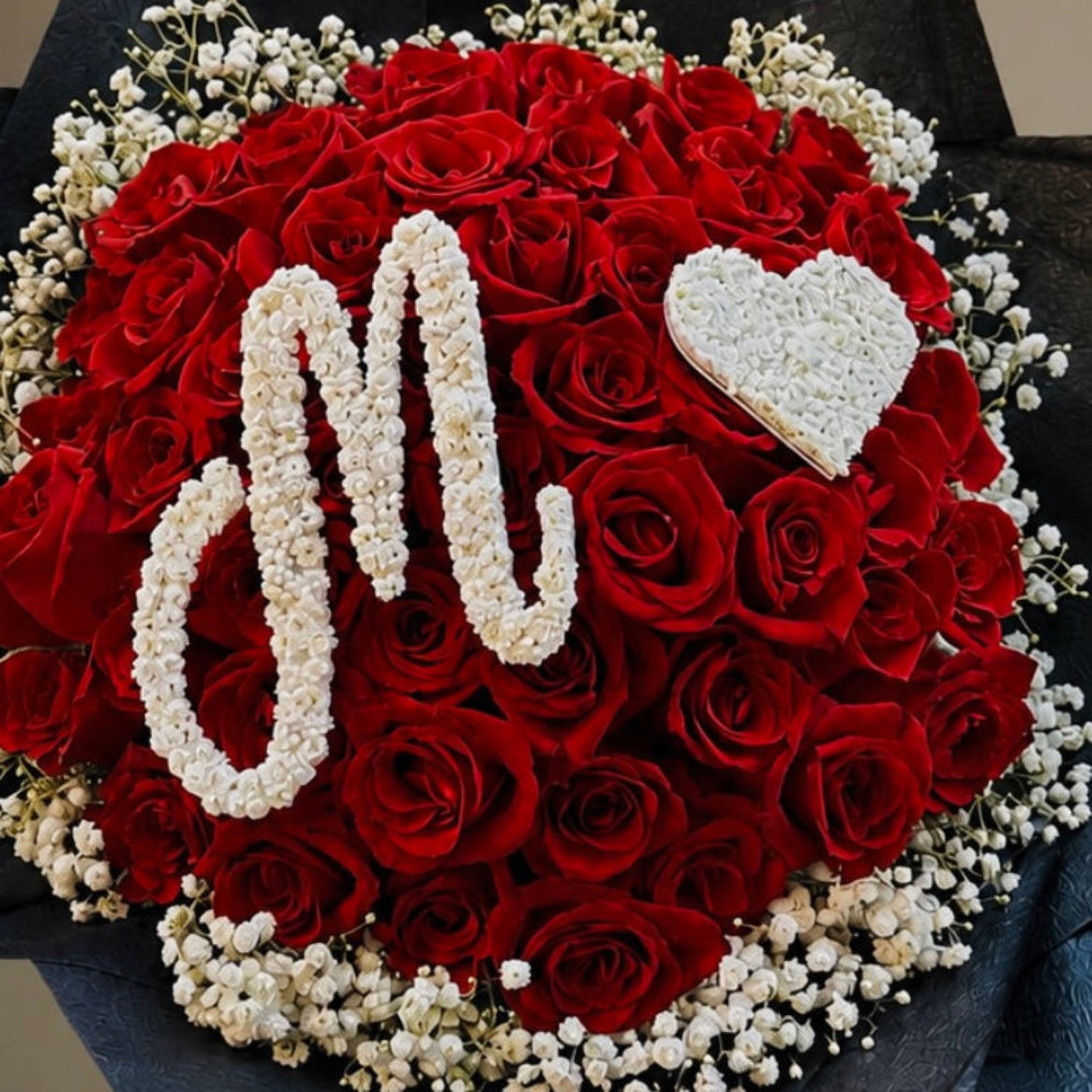 A bouquet of red roses with baby’s breath initial  letter 'M' and a white heart, surrounded by white baby's breath